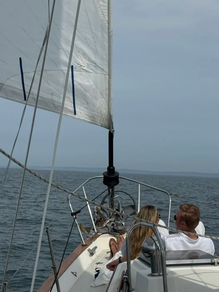 Couple dressed in all white enjoying sailboat ride from the bow