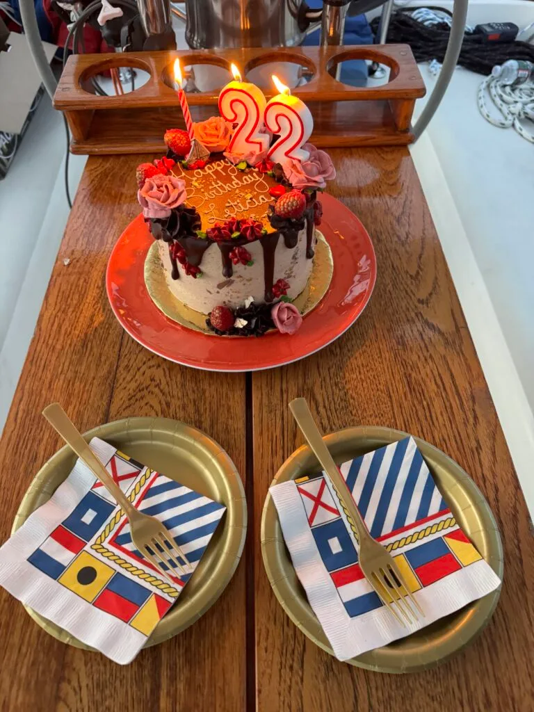 Birthday cake and charcuterie board set out in the cockpit of Our Passion with nautical flags