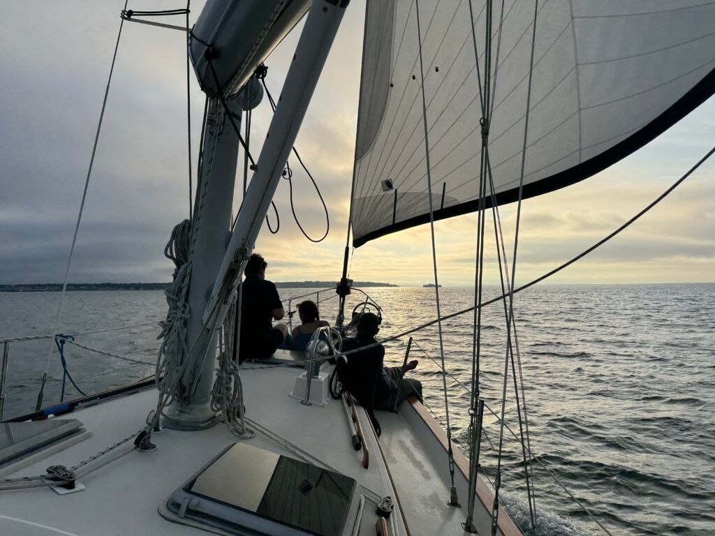 family on bow of sailboat enjoying the sunset