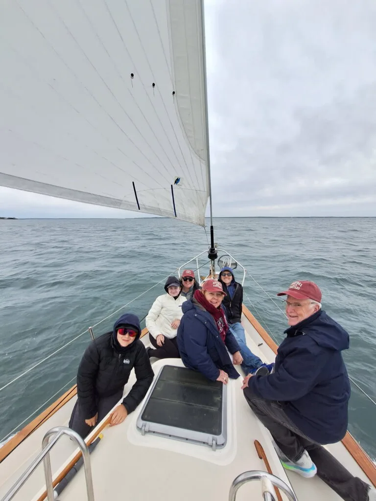 Three generations of family seated together on the bow of a sailing charter on Vineyard Sound, Martha's Vineyard