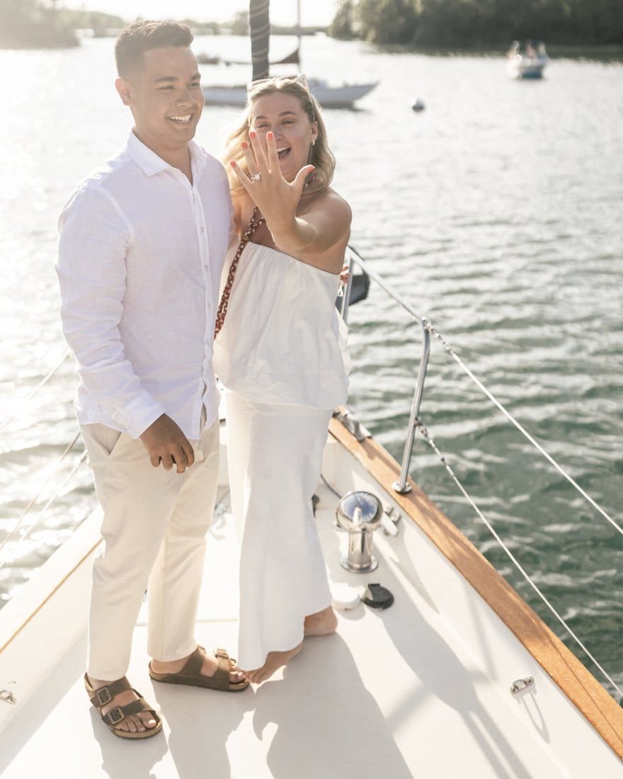 A newly engaged couple on the bow of Our Passion during a private sailing charter