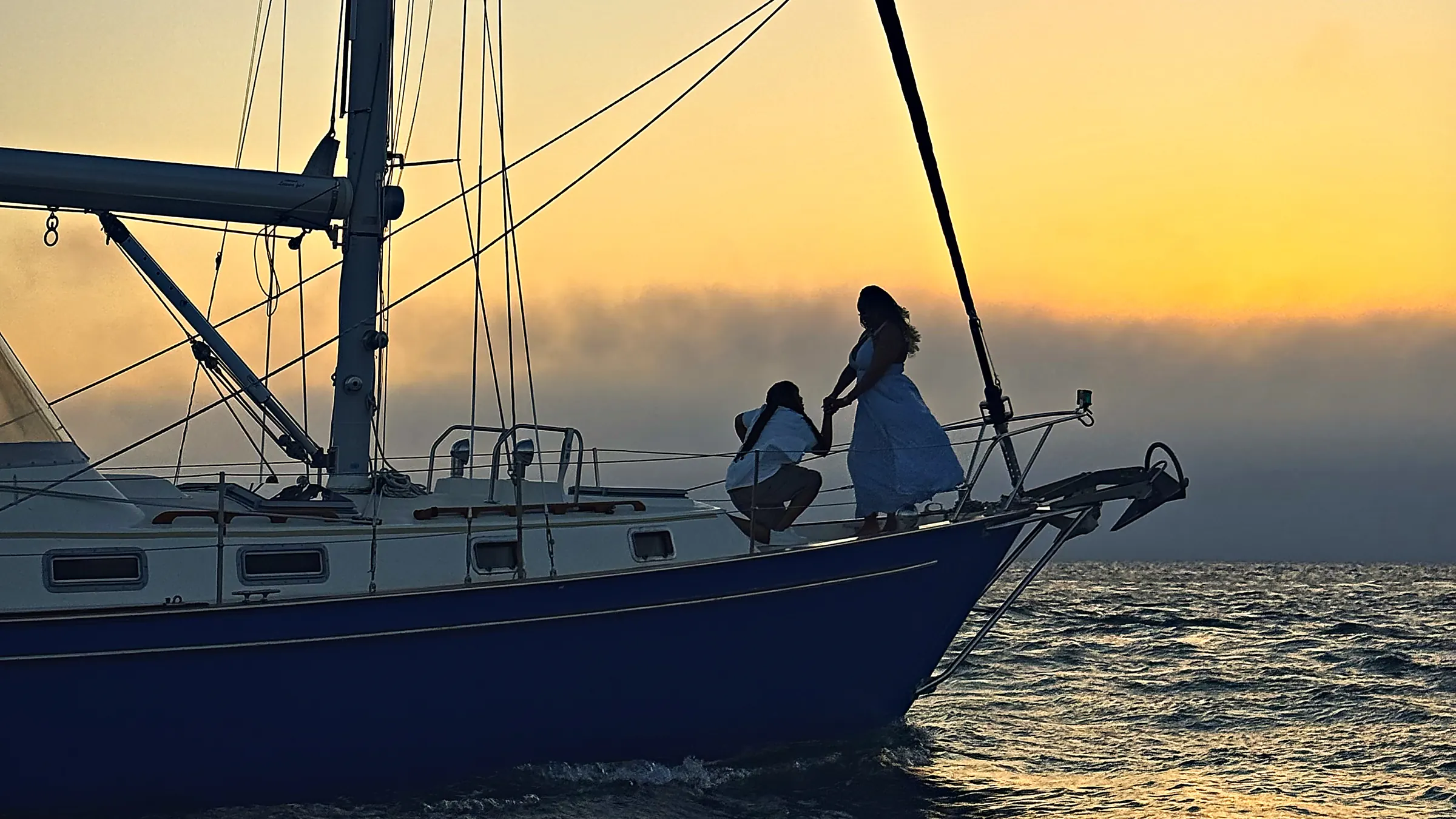 Couple getting engaged at sunset on the bow of Our Passion during a private Martha's Vineyard sailing charter